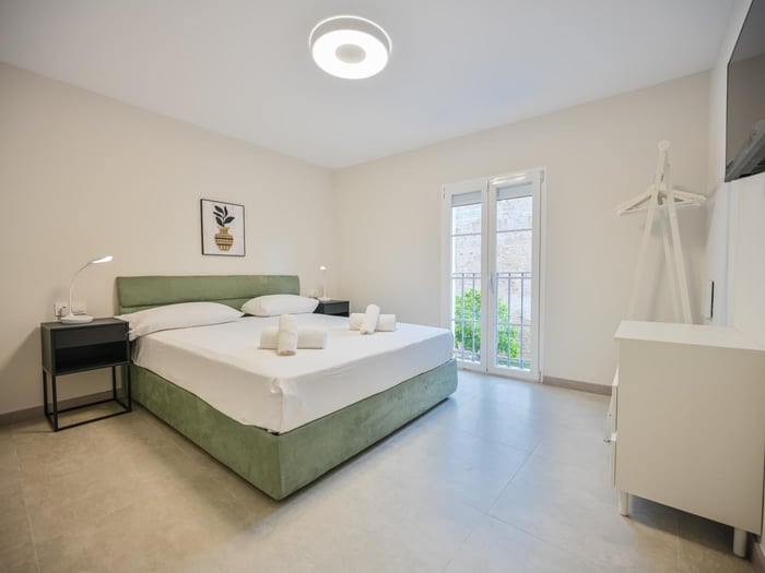 Double bed in bedroom with air conditioner and flatscreen TV